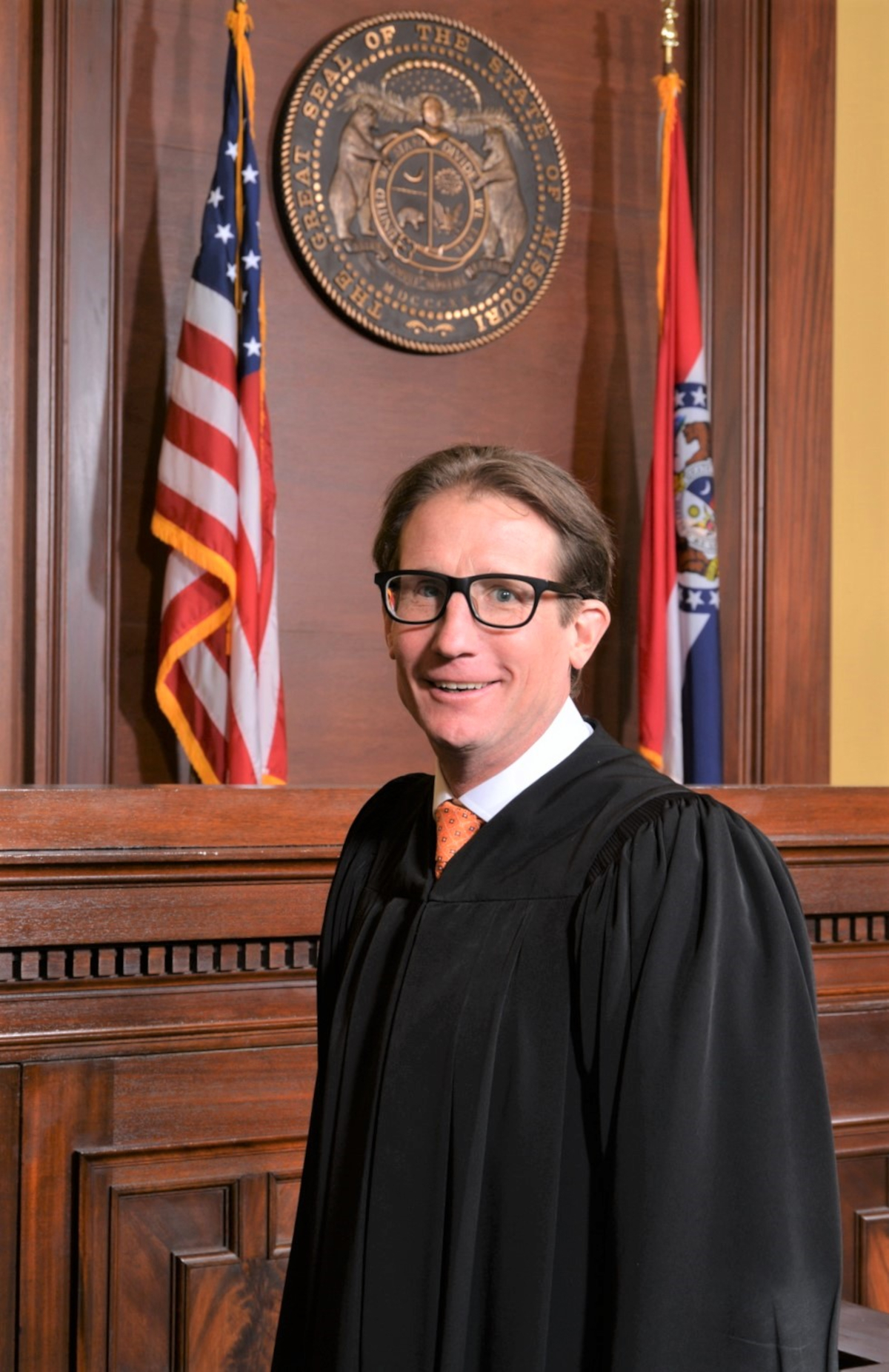 Brent Powell portrait, in black robe in front of Missouri seal and flag in courtroom