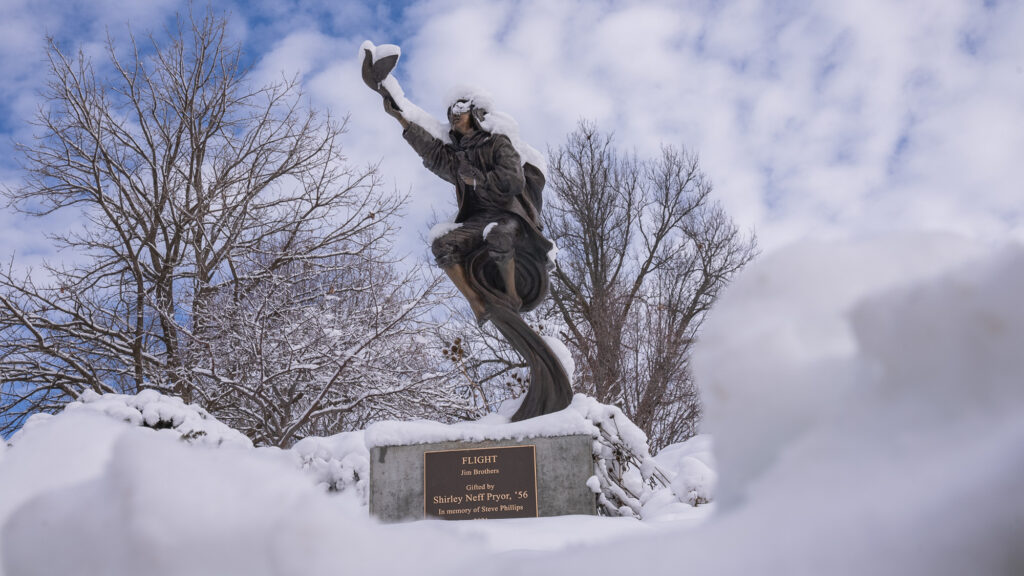 Snow-covered bronze "Flight" sculpture surrounded by deep winter snow on the William Jewell College campus.