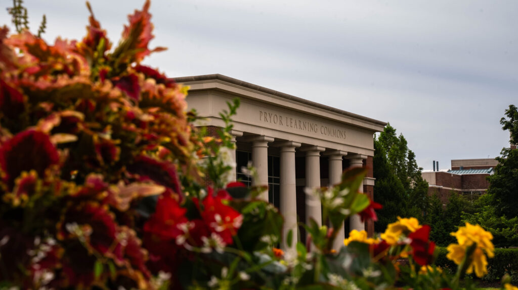 Exterior front view of Pryor Learning Commons at William Jewell College framed by vibrant red and yellow garden flowers.
