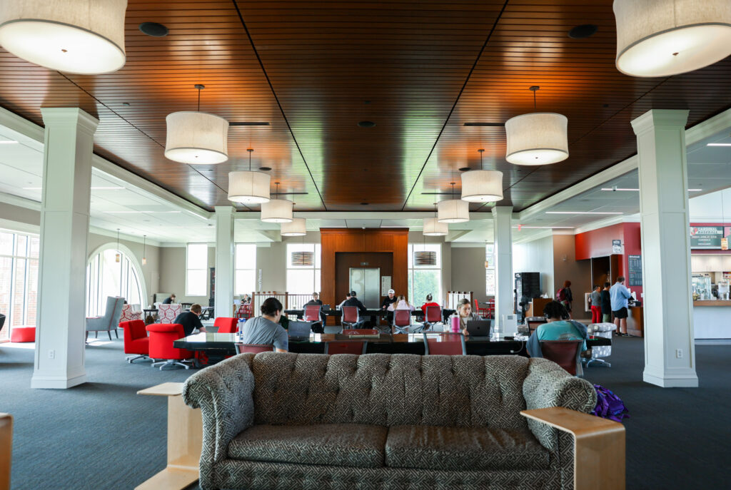 Interior view of Pryor Learning Commons at William Jewell College showing open study tables, lounge seating, and large pendant lighting.