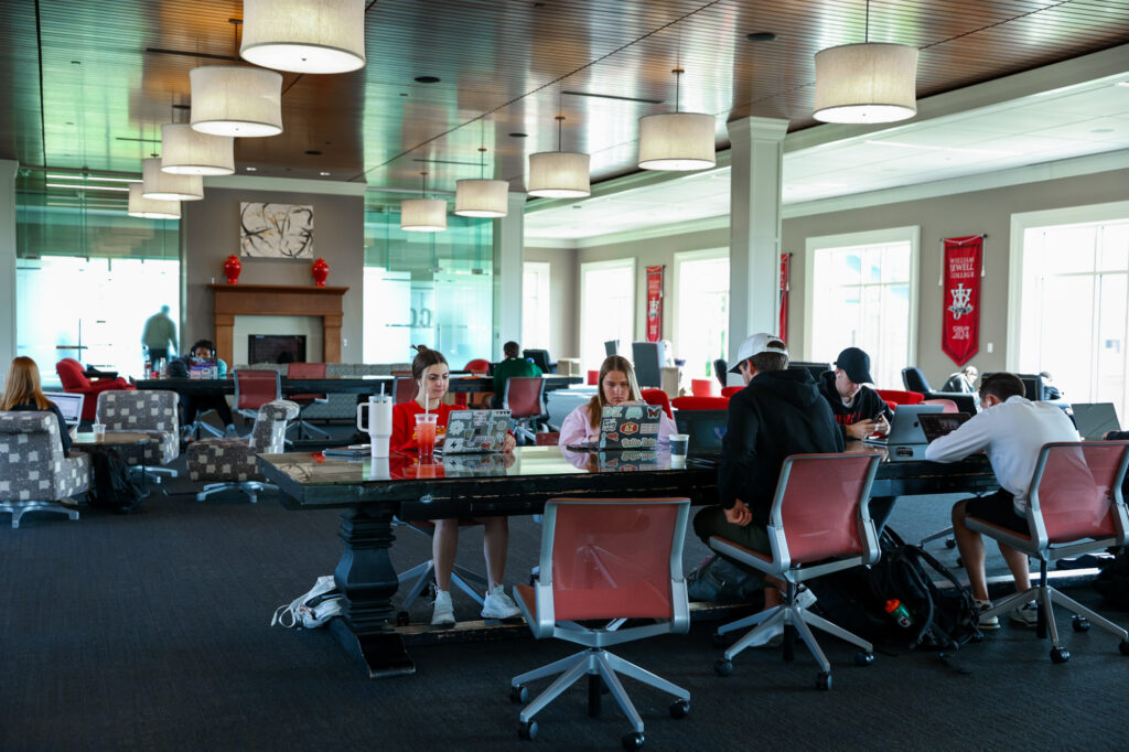 Students studying with laptops around a large central work table in the Pryor Learning Commons at William Jewell College.