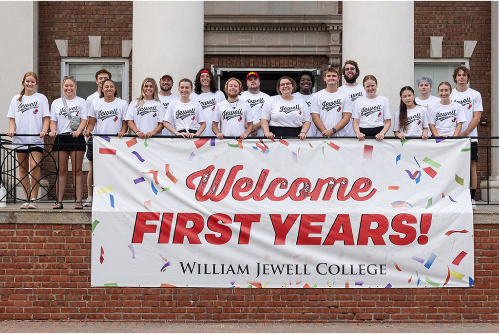 Orientation leaders in matching white t-shirts standing behind a banner reading "Welcome First Years!"