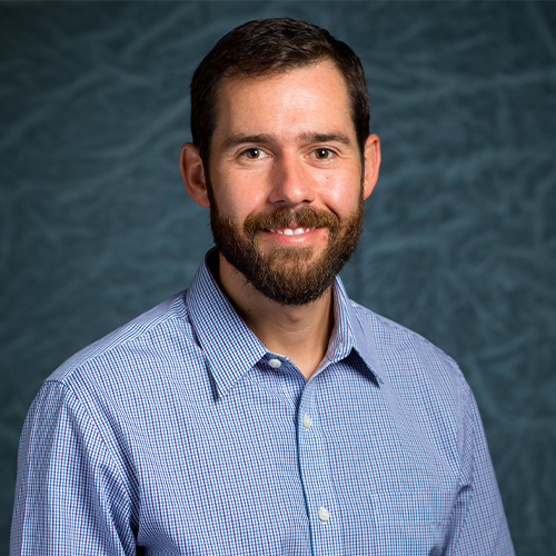Headshot of Dr. David Lisenby, Professor of Spanish at William Jewell College, wearing a blue patterned button-down shirt against a gray backdrop.