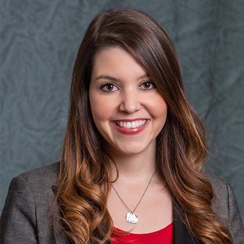 Headshot of Marissa Bland, Adjunct Instructor in College Wide Courses and Director of Career Development and Internships at William Jewell College, smiling with long wavy brown hair, wearing a red top and blazer against a gray backdrop.