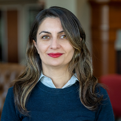 Headshot of Dr. Mahsa Hosseini, Assistant Professor of Biochemistry at William Jewell College, smiling with shoulder-length dark wavy hair, wearing a dark sweater over a collared shirt.