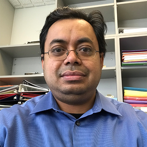 Headshot of Dr. Taqsim Husnain, Associate Professor of Civil Engineering at William Jewell College, wearing glasses and a blue button-down shirt in an office setting.