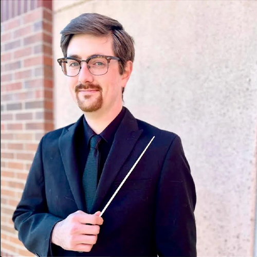 Headshot of Lawrence Abernathy, Assistant Professor of Music and Interim Director of Choral Studies at William Jewell College, wearing glasses and a suit while holding a conductor's baton.