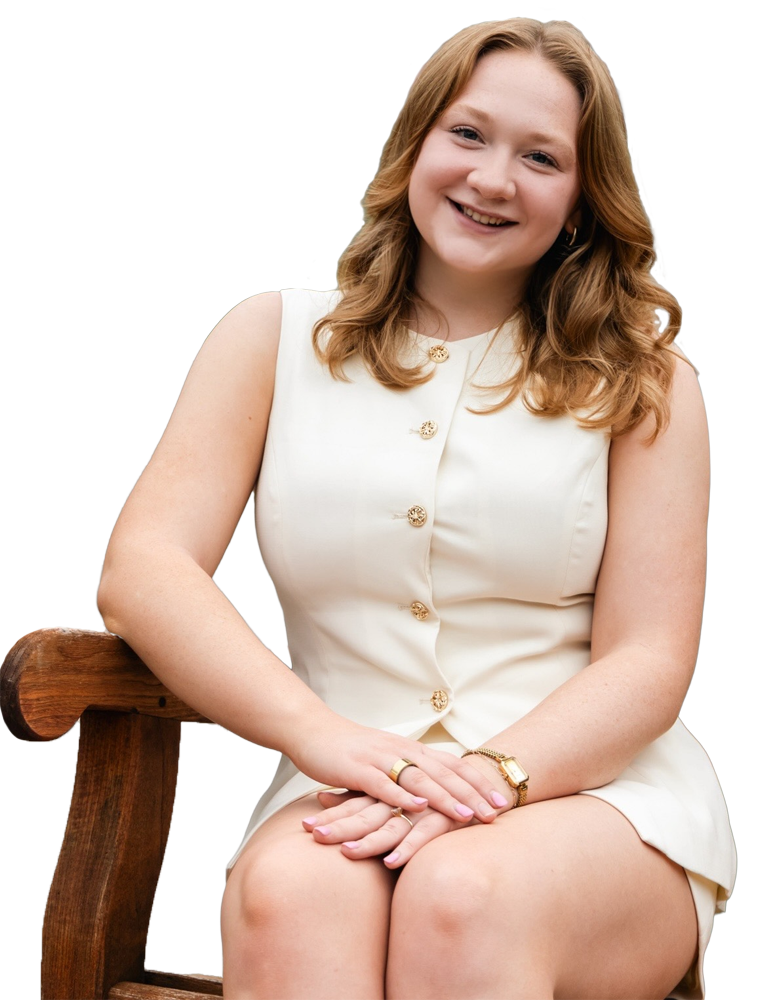 Jamie Schenck smiling in a cream button-front sleeveless dress seated outdoors.
