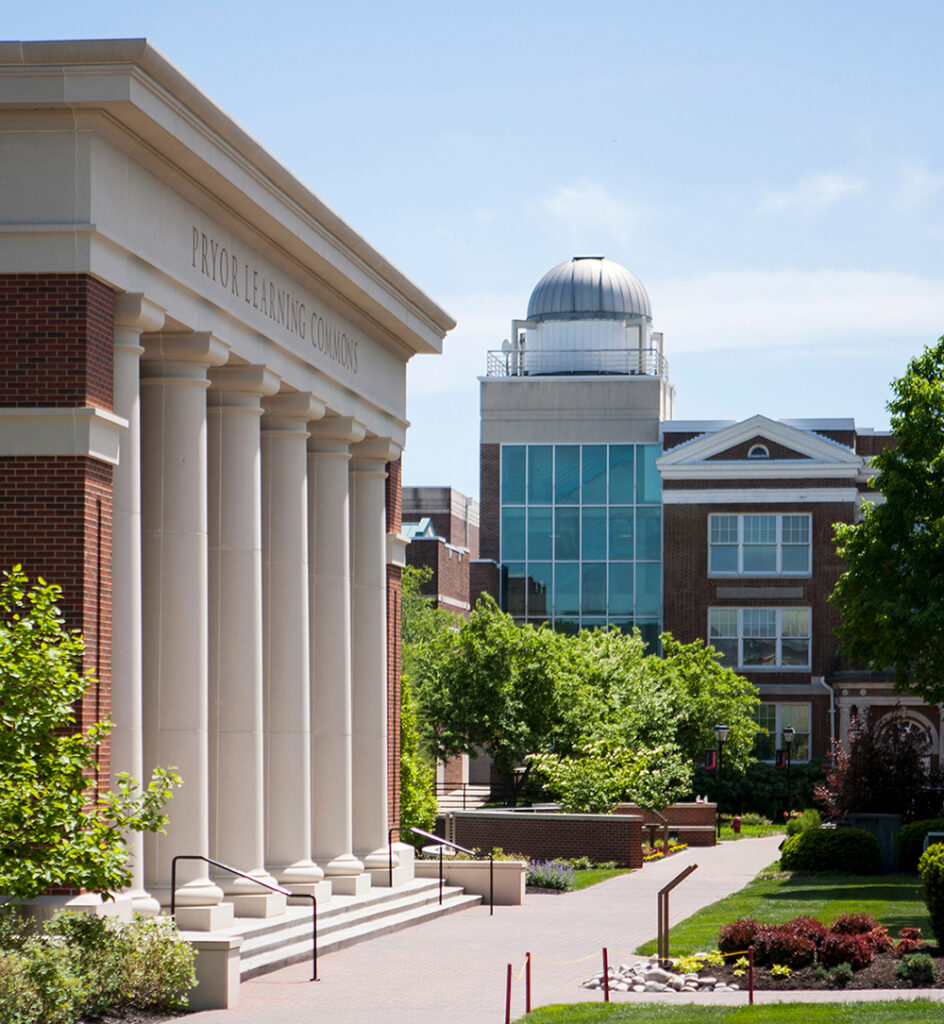 A side view of the Pryor Learning Commons entrance with the White Science Center observatory dome visible in the background.