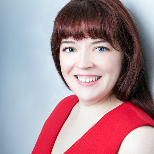 Headshot of Erin Lillie, Adjunct Instructor in Music - Voice at William Jewell College, with reddish-brown hair and bangs, wearing a red sleeveless top against a light background.