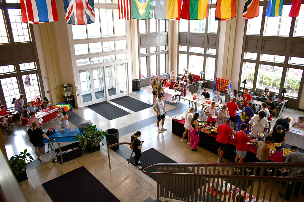 High-angle view of students gathering in the Yates-Gill College Union atrium for an organization fair surrounded by international flags.