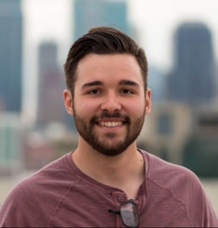 Dalton Nelson, a mathematics and physics student at William Jewell College, smiling outdoors in front of a blurred city skyline.