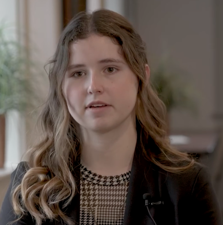 Victoria Pascoe, a philosophy student at William Jewell College with long wavy hair wearing a dark blazer, speaking in a student spotlight video.
