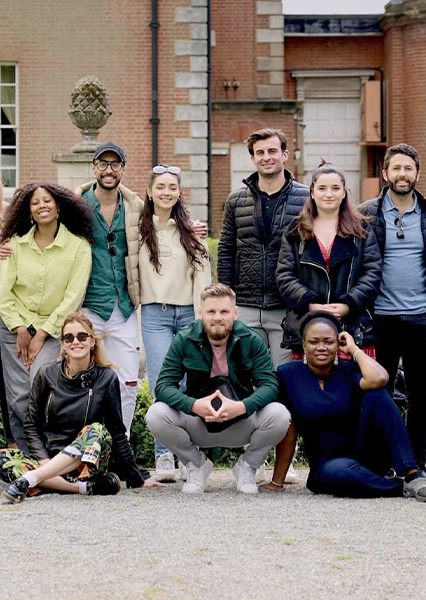 A group of Executive MBA students sitting and standing together outdoors in front of a brick building.