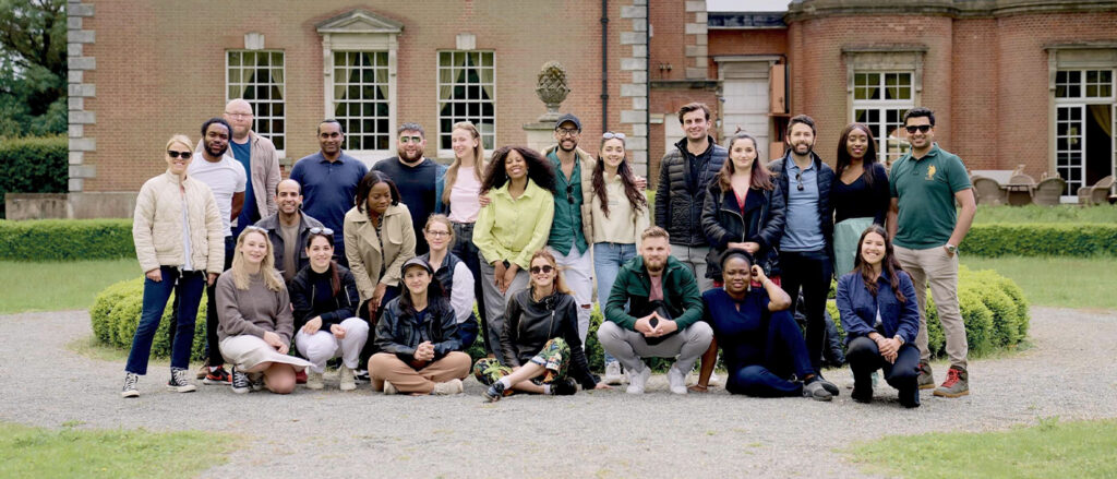 A large group of Executive MBA students posing together outdoors in front of a brick building.