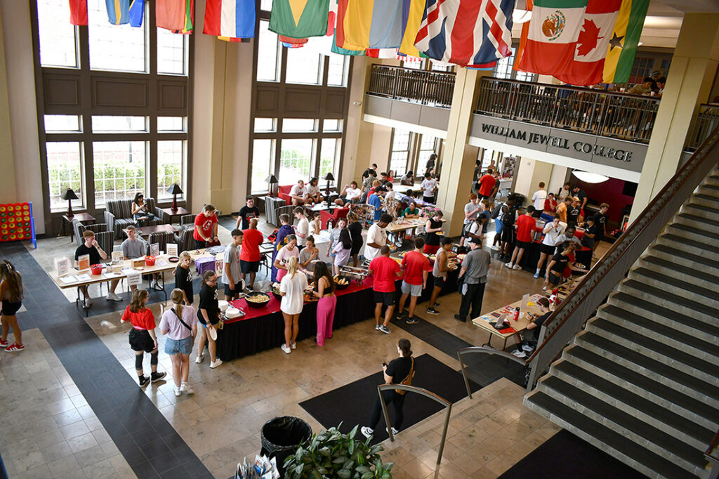 High-angle view of students visiting information tables and eating food during an organization fair in the Yates-Gill College Union atrium.