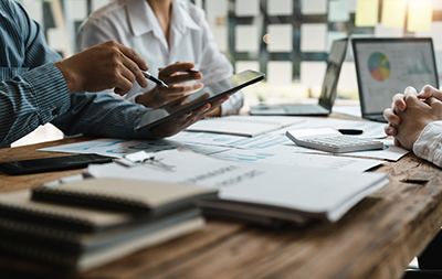 A close-up view of professionals reviewing financial charts and data together using a digital tablet and laptop.