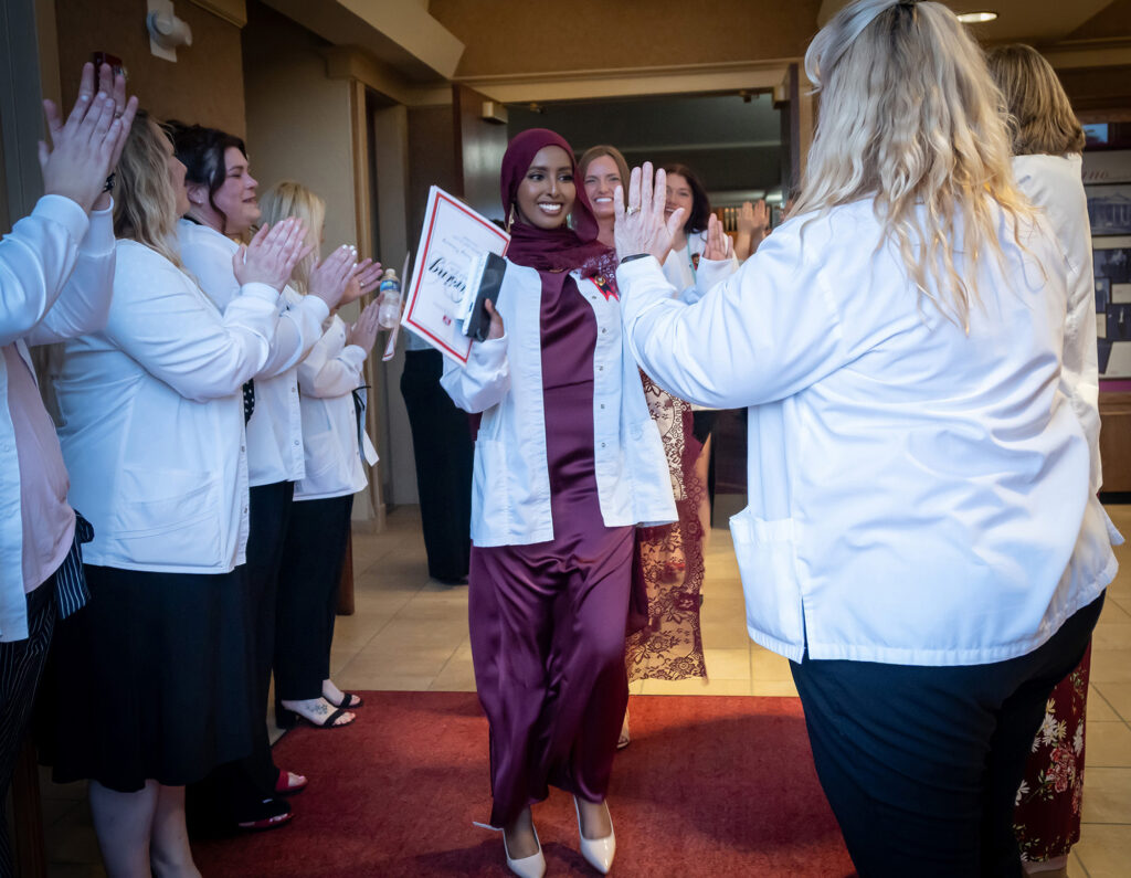 nursing professors congratulating nursing grads with high fives, hugs