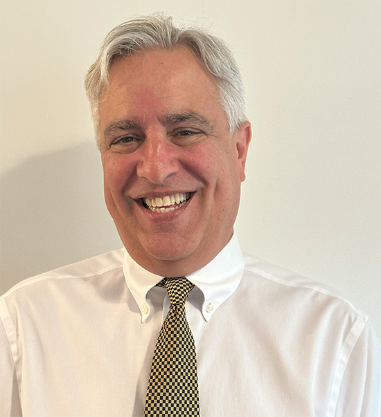 Faculty headshot of professor wearing a white button-down shirt and a tie.