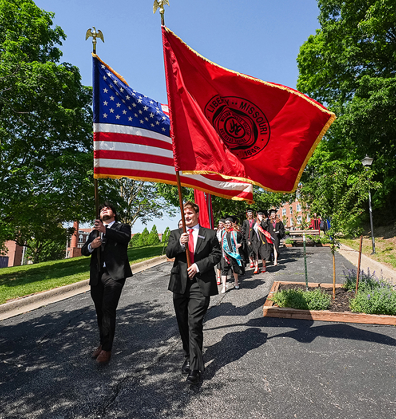 American and Jewell flag bearers leading line of graduates around campus