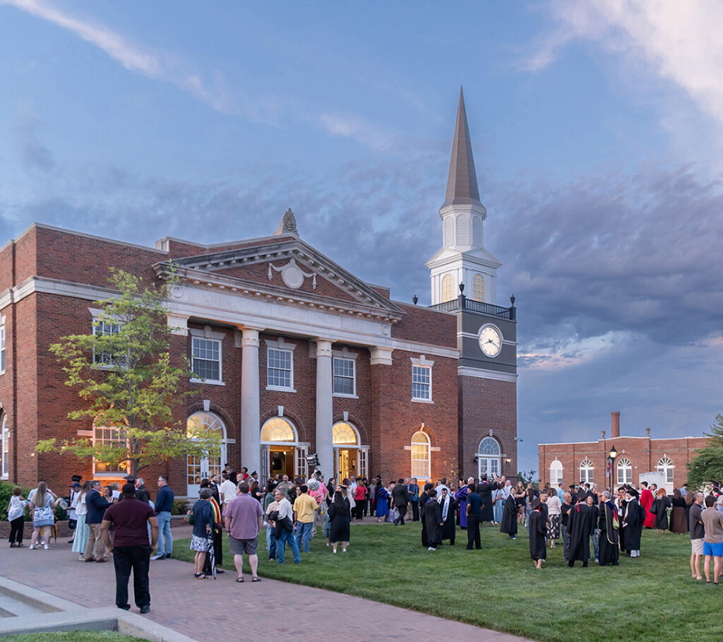 Students, faculty, and guests gathering on the lawn outside John Gano Memorial Chapel during an evening campus event.