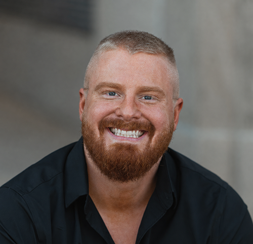 Vann Bradham, Exercise Science faculty member, smiling with a short beard in a black button-down shirt.