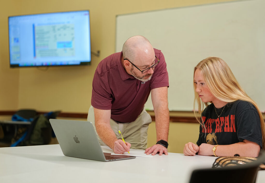 professor reviewing notes with student in classroom