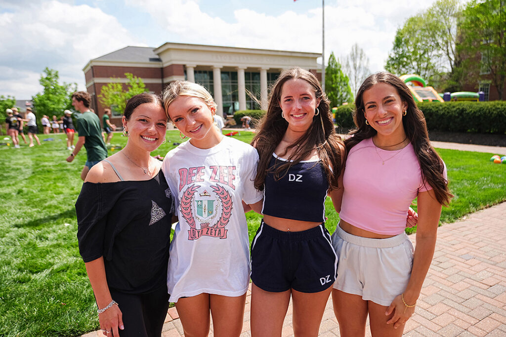 4 girls on campus lawn, posing
