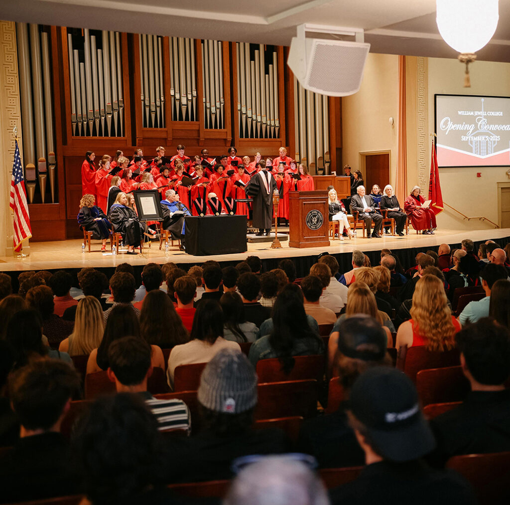 college choir in red choir robes singing on chapel stage