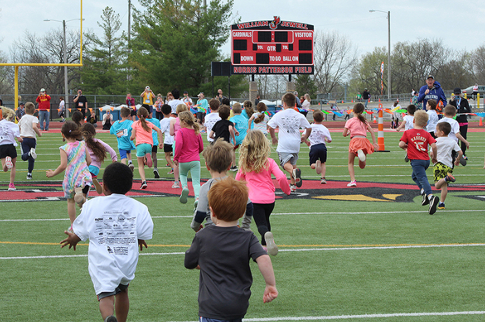Kids running across Jewell football field during Kids Fun Run event