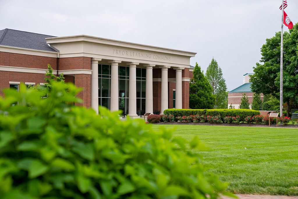 summer green lawn and flowers with red brick building with columns in background