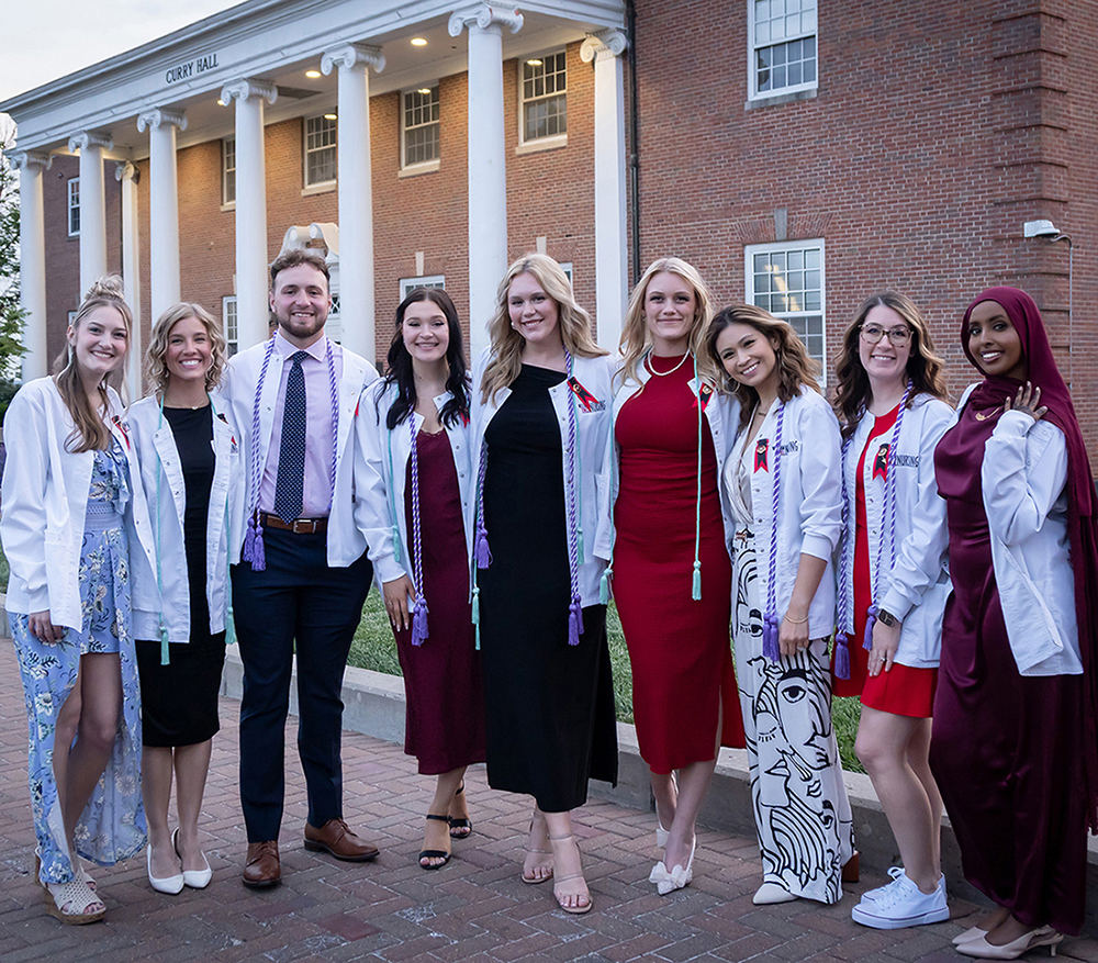 group of accelerated nursing students in white coats at nursing pinning ceremony