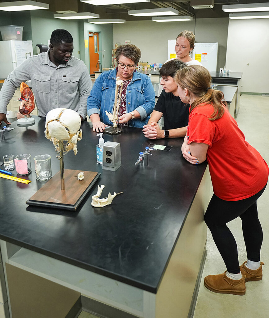 students gathered around professor with a bone model in anatomy lab