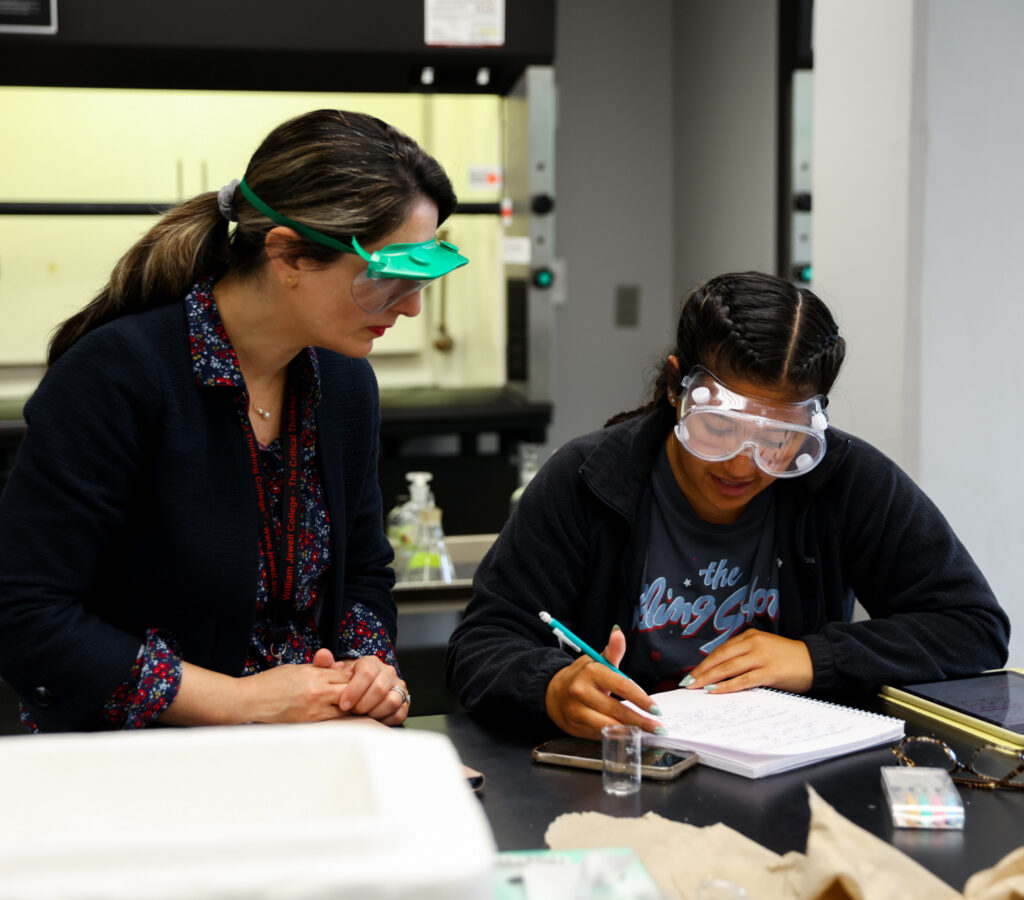 professor helping student with written assignment in chemistry lab