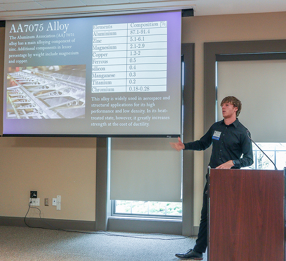 male student at lectern standing in front of presentation on a screen