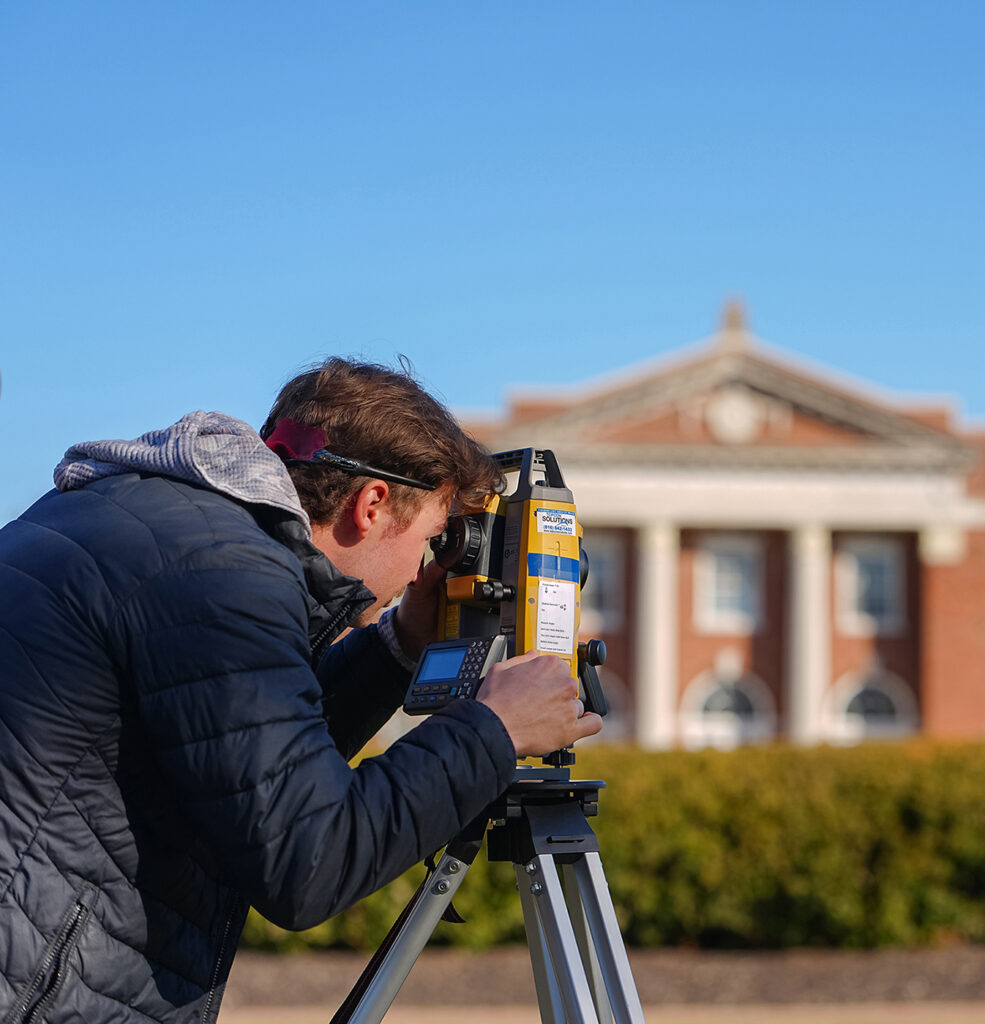 engineering student using survey equipment on campus