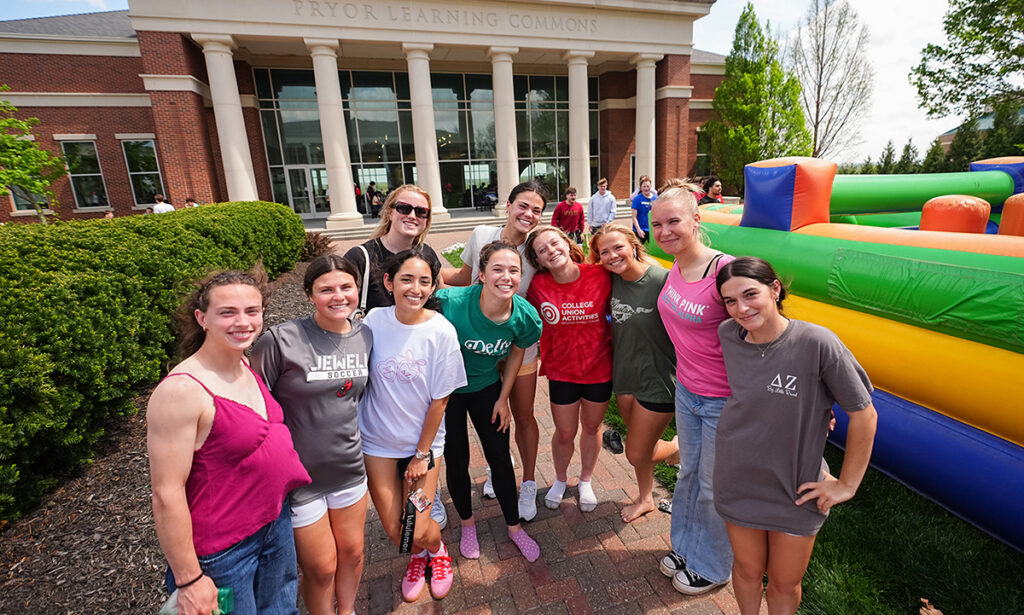 group of girls posing outside on campus by inflatable game