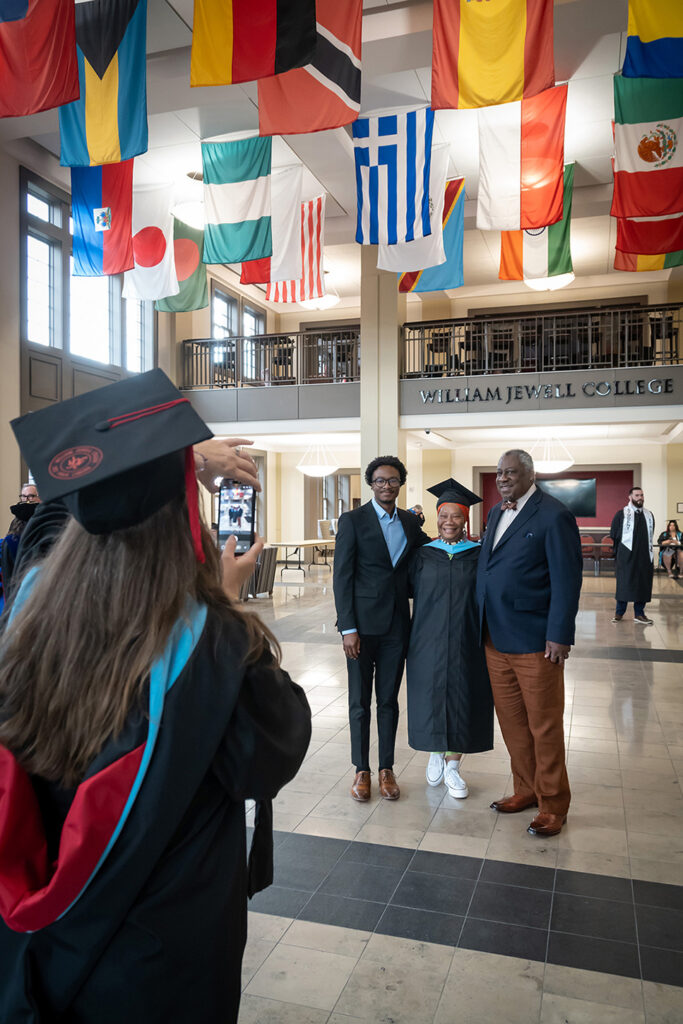 student in graduation cap and gown having photo taken with her family