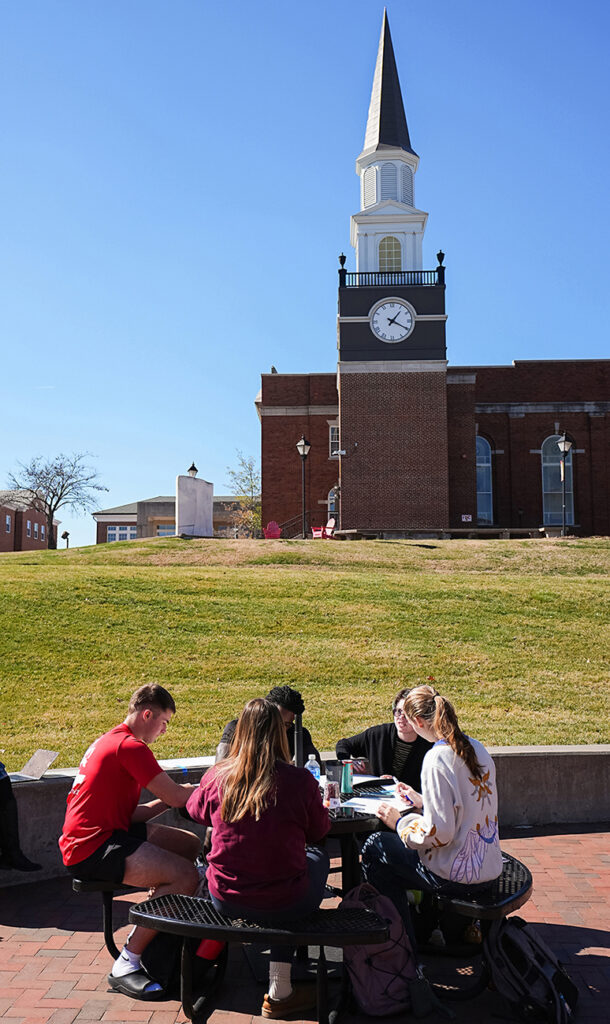 group of students studying together at table outside
