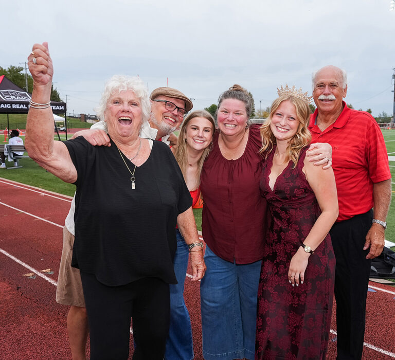 newly crowned homecoming queen posing with family on football field