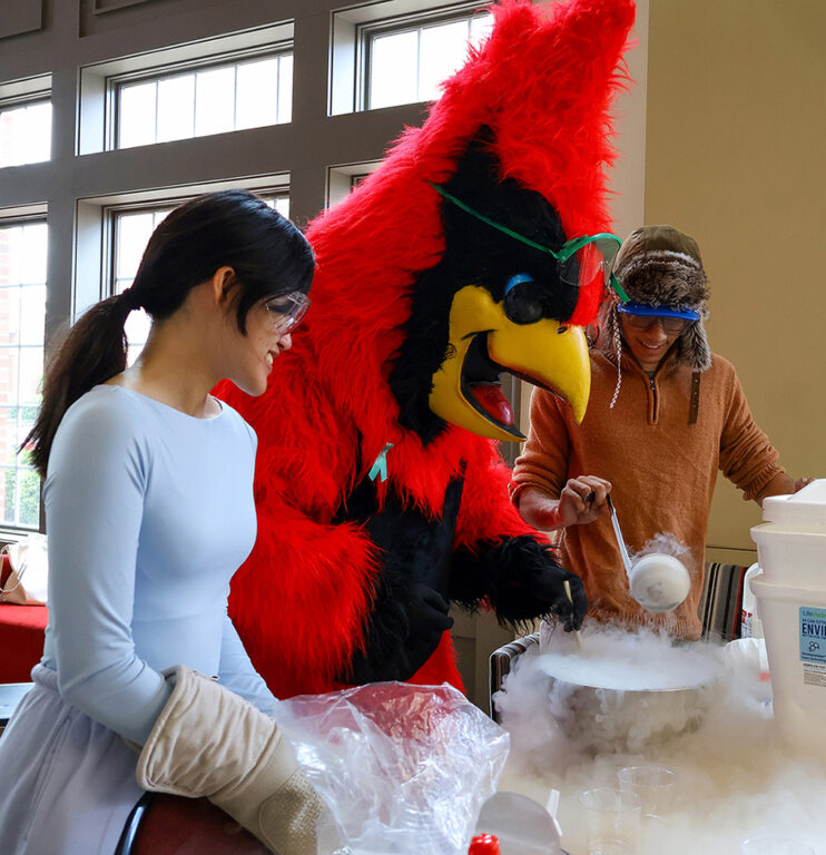 2 students with cardinal mascot stirring liquid nitrogen ice cream bowl