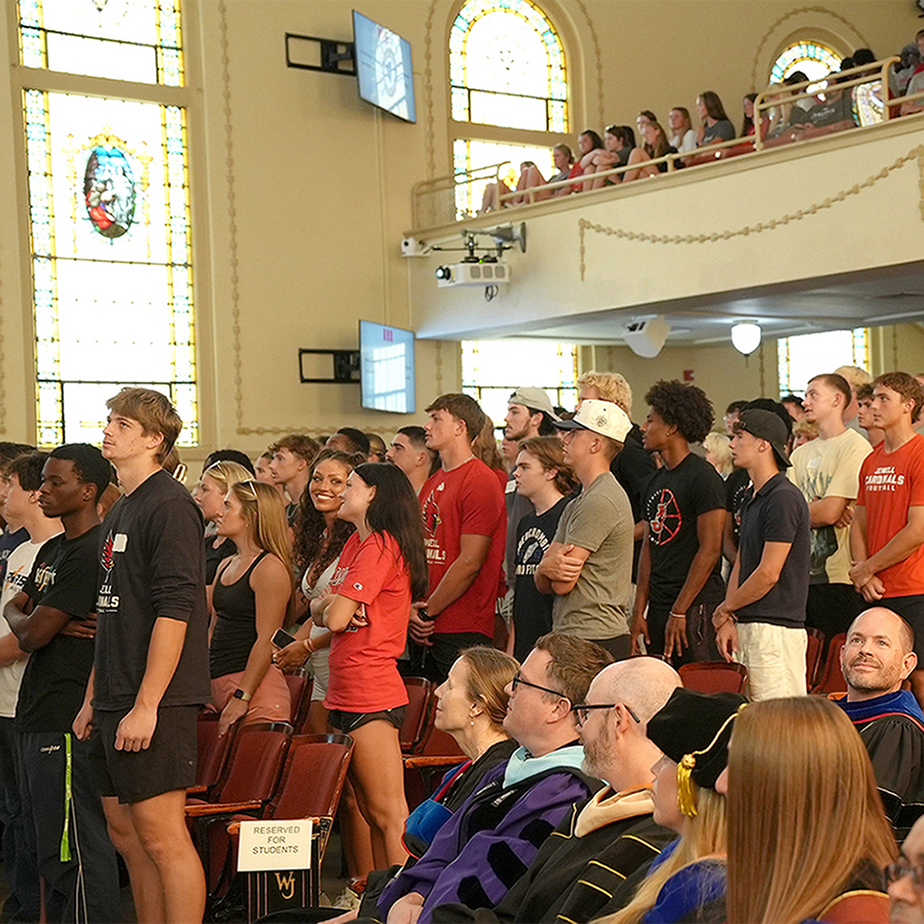 new students standing in auditorium for matriculation ceremony