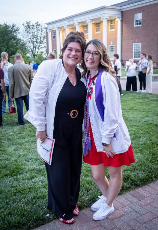 nursing professor with arm around nursing graduate after pinning ceremony