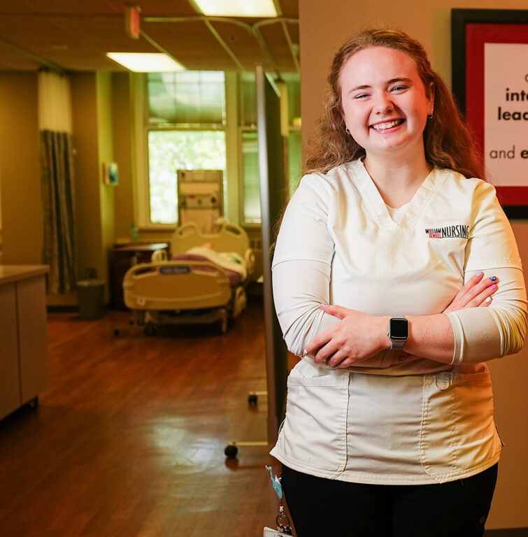 nursing student standing by hospital bed in nursing lab