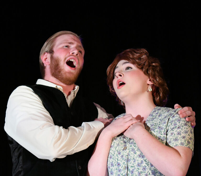 man and woman on stage singing in opera