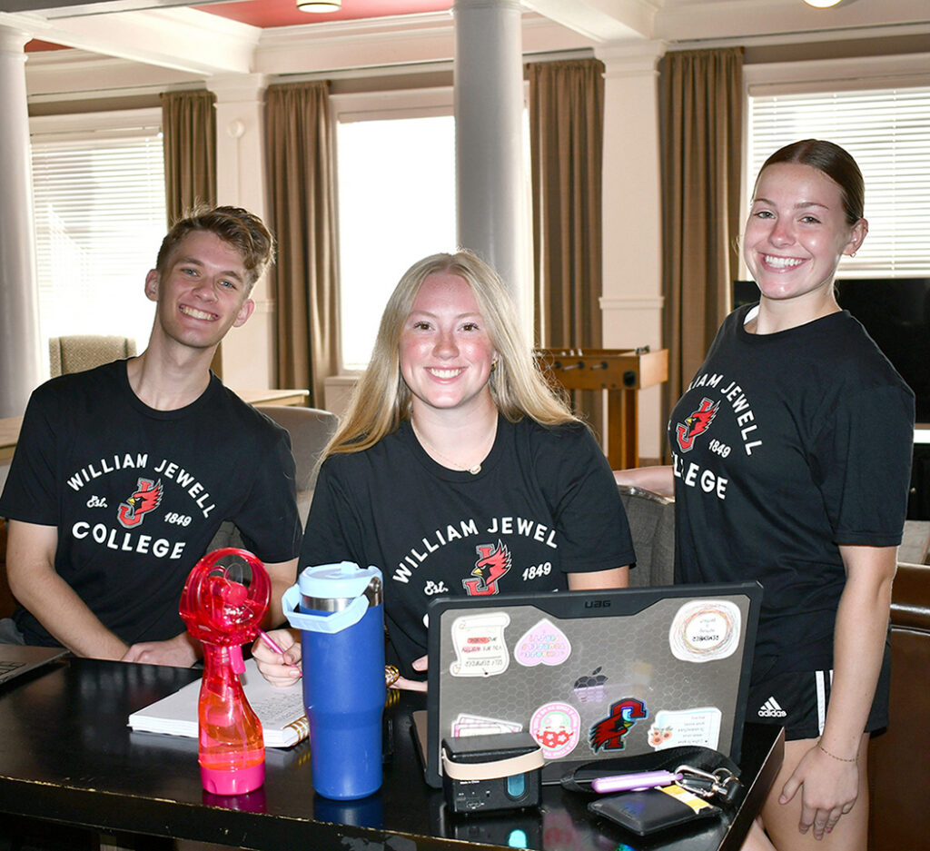 3 resident assistants in black T-shirts at check-in table during move-in