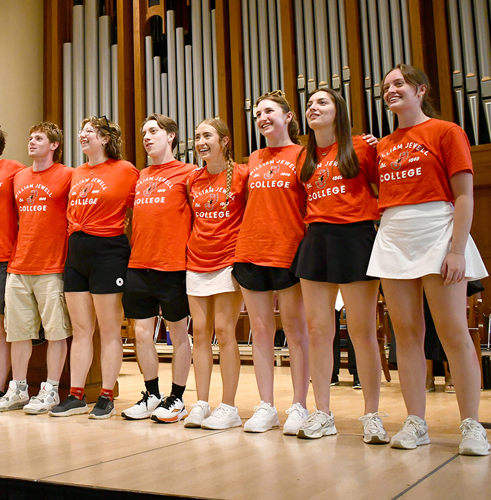 orientation mentors on stage, arm locked, singing