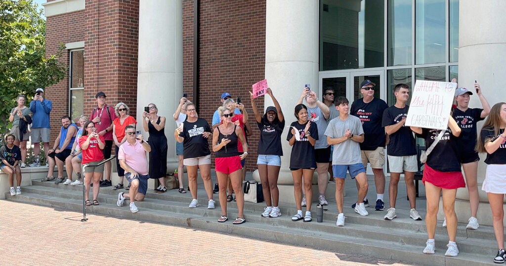 parents cheering, taking pictures as new students walk by on quad during orientation
