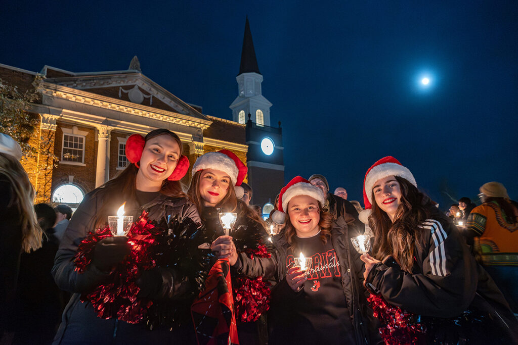 students outside at night holding candles during holiday lighting ceremony