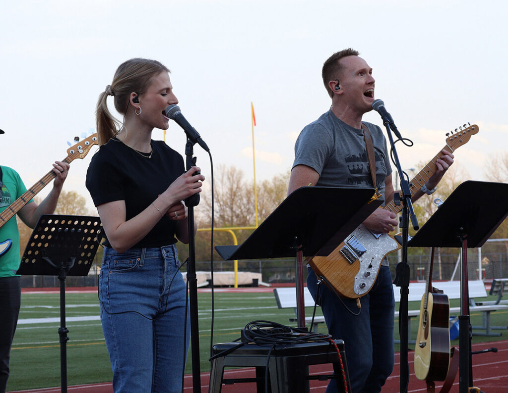 singers with guitars peforming on college football field